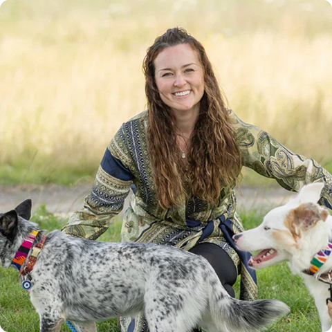 Woman sitting outdoors with two dogs on a leash